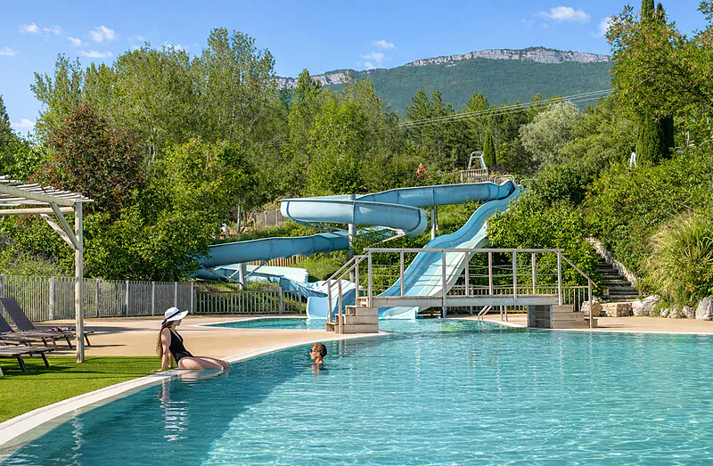 Outdoor swimming pool, water slides and sun loungers at CLICOCHIC Couriou campsite in Recoubeau-Jansac.