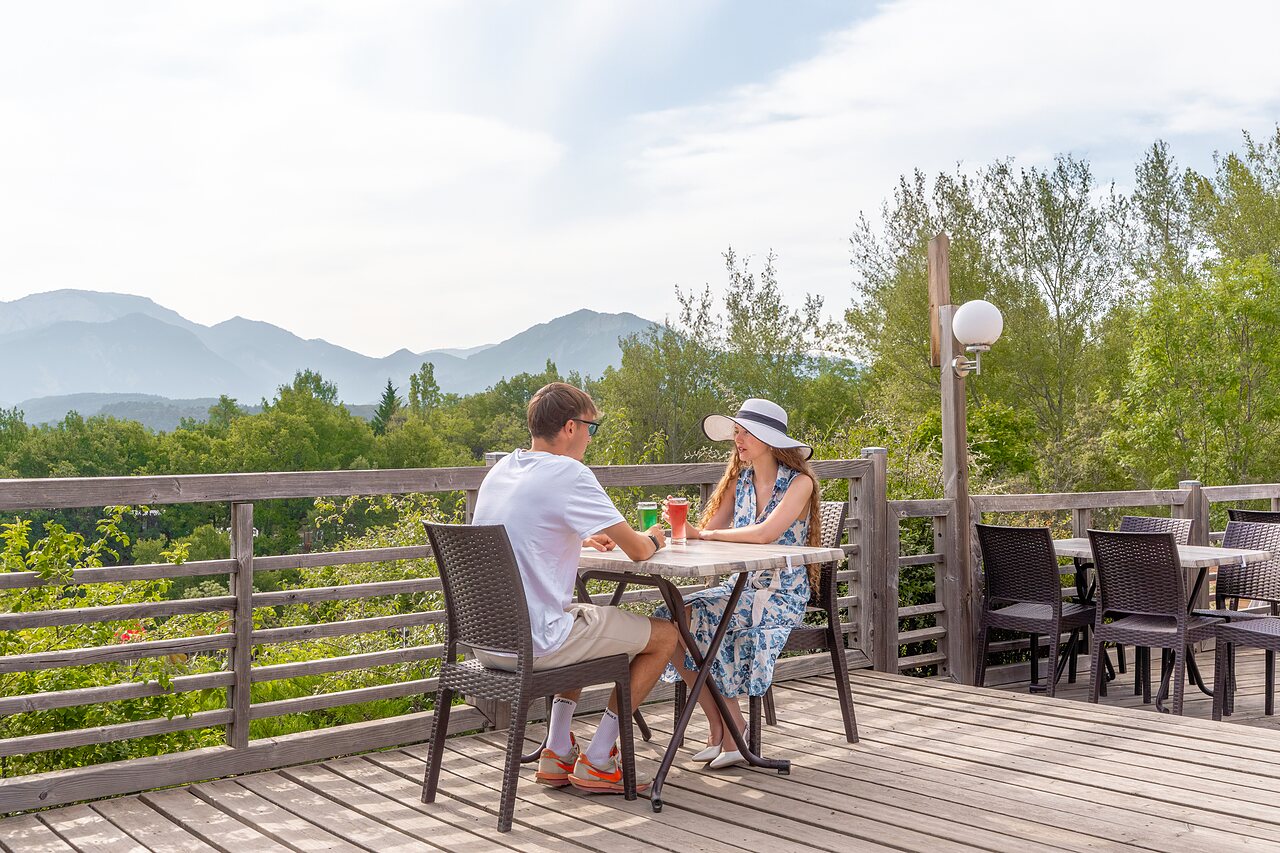 Couple restaurant terrace, mountain view, at CLICOCHIC Couriou campsite in Recoubeau-Jansac.
