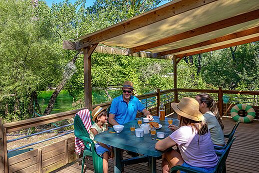 Family having breakfast terrace Mobil-home river view at campsite CLICOCHIC Coutelière in Lagnes.