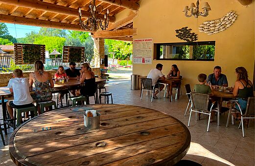 Covered restaurant and bar area with families at camping CLICOCHIC Coutelière (84).