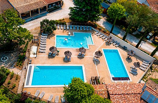 Aerial view of multiple pools with chairs at camping CLICOCHIC Coutelière in Lagnes (84).