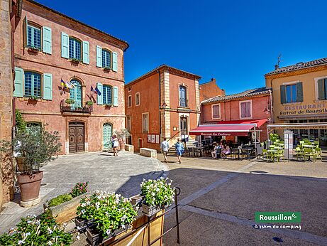 Central square of Roussillon village, colorful houses and restaurant in Provence.