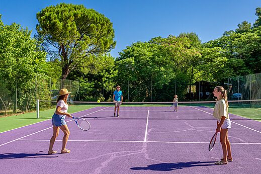 Family playing tennis on a purple court at CLICOCHIC Coutelière campsite in Lagnes (84).