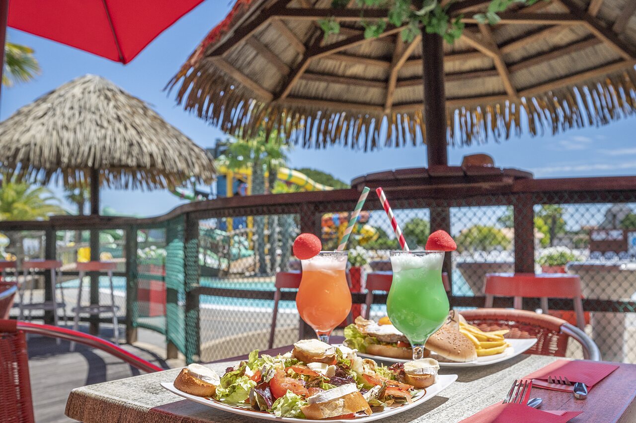 Dishes and cocktails on the restaurant terrace with pool at CAPFUN Curty's campsite in Jard sur Mer (85).