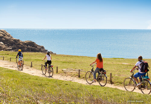 Family cycling on coastal path by the sea at CAPFUN Dauphins Bleus campsite in GIVRAND (85).