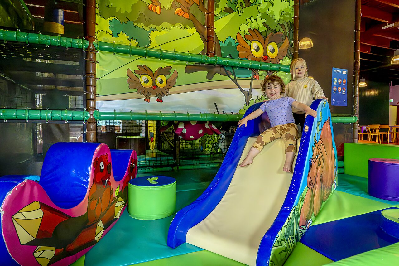 Happy children on slide and indoor play area at CAPFUN De Belten campsite in Rheeze