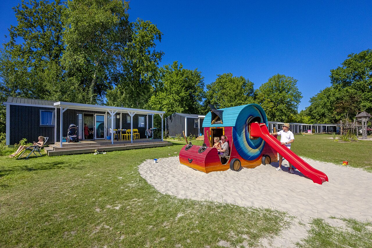 Colorful playground with slide and mobile homes at CAPFUN De Belten campsite in Rheeze.