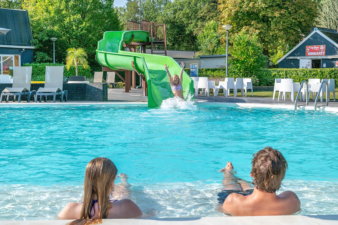 Water slide and outdoor pool with children playing at CAPFUN De Belten campsite in Rheeze.