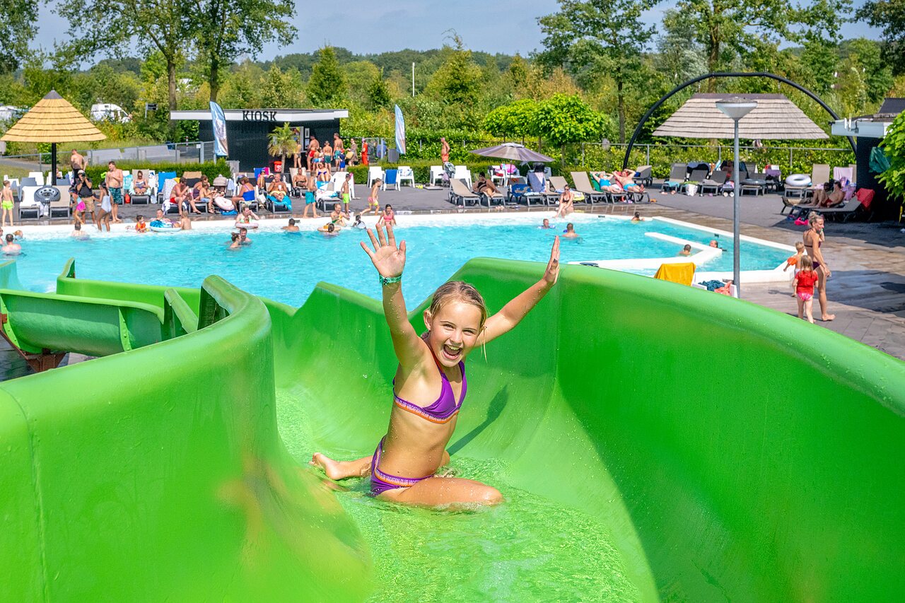 Girl on water slide, outdoor swimming pool at CAPFUN De Belten campsite in Rheeze.