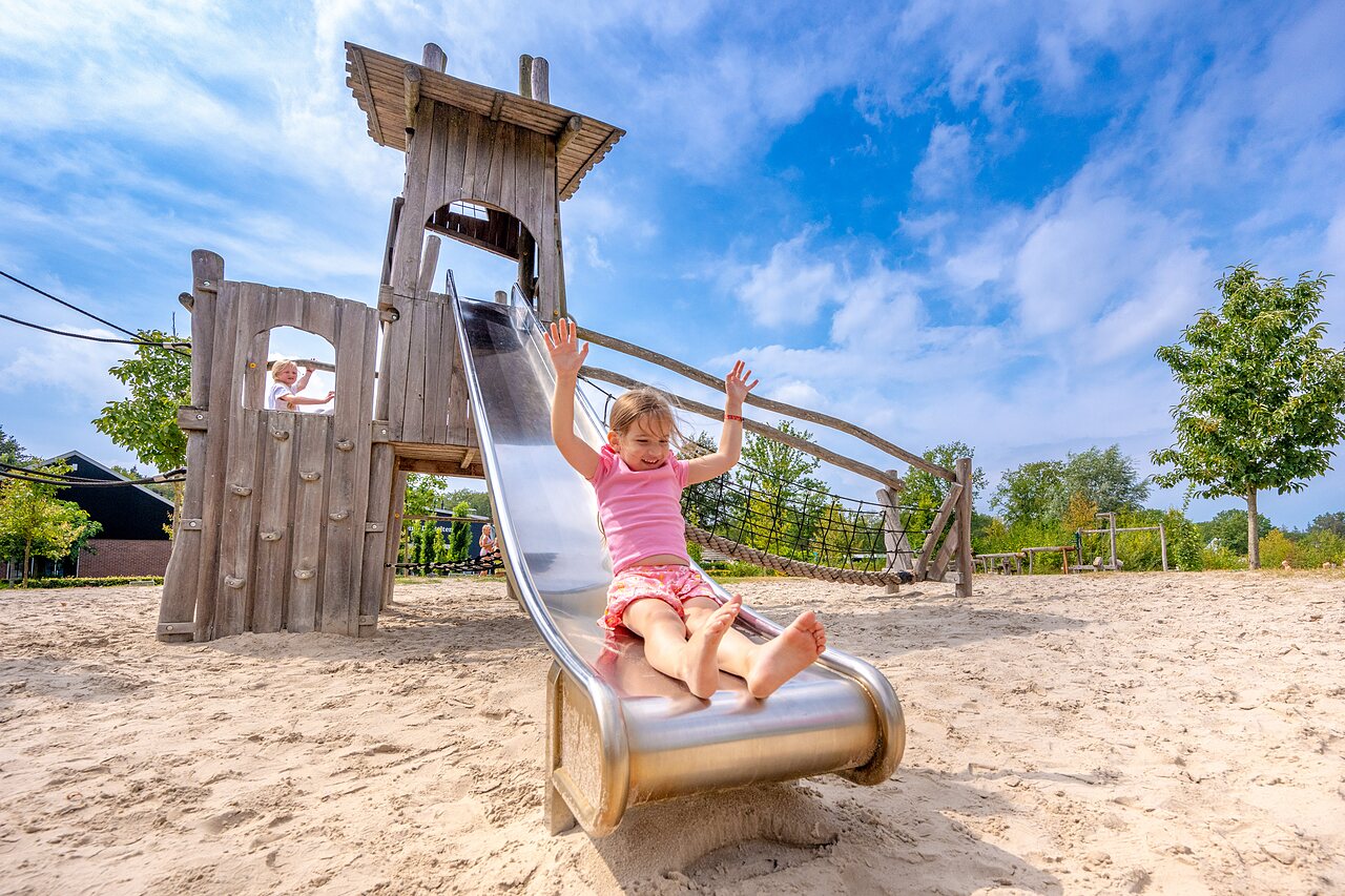 Children enjoying slide and wooden playground at CAPFUN De Belten campsite in Rheeze.