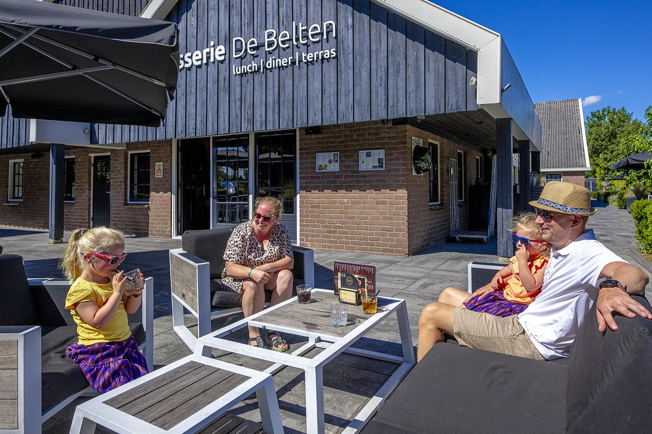 Family enjoying the brasserie terrace at CAPFUN De Belten campsite in Rheeze.