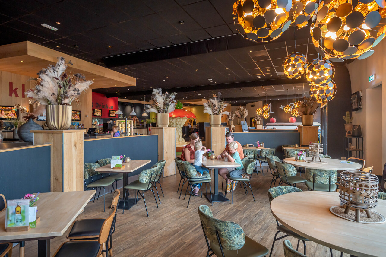 Modern restaurant, families, tables, chairs at CAPFUN De Bongerd campsite in Tuitjenhorn.