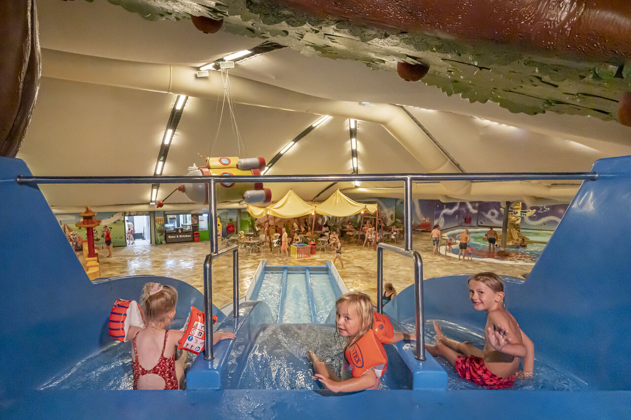 Children playing on the indoor water slide at CAPFUN De Bongerd campsite in Tuitjenhorn.