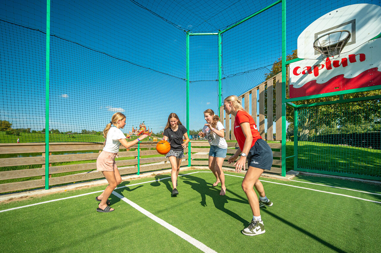 Girls playing basketball on multisport court at CAPFUN De Bongerd campsite in Tuitjenhorn.