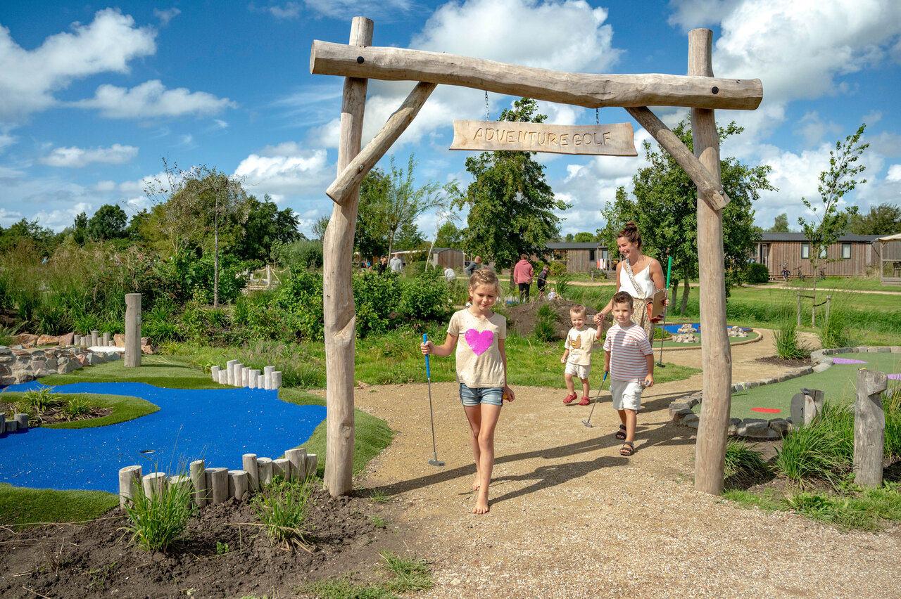 Family playing adventure mini-golf on a fun course at CAPFUN De Bongerd campsite in Tuitjenhorn.