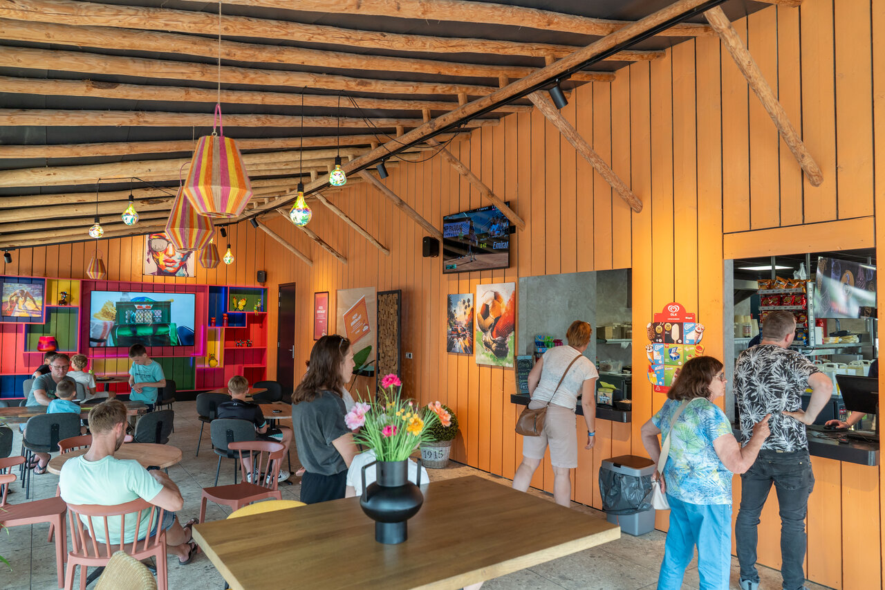 Colorful indoor restaurant and bar with guests at CAPFUN De Bongerd campsite in Tuitjenhorn.