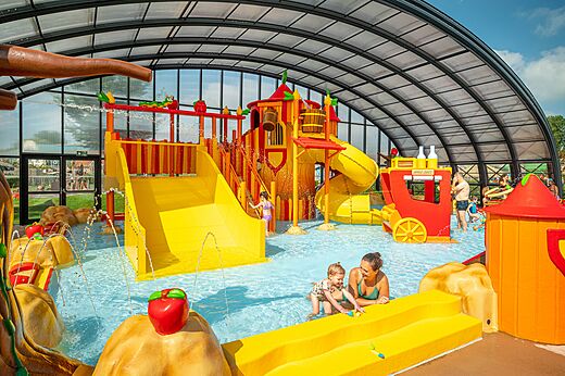 Indoor water play area with slides and children at CAPFUN De Bongerd campsite in Tuitjenhorn.