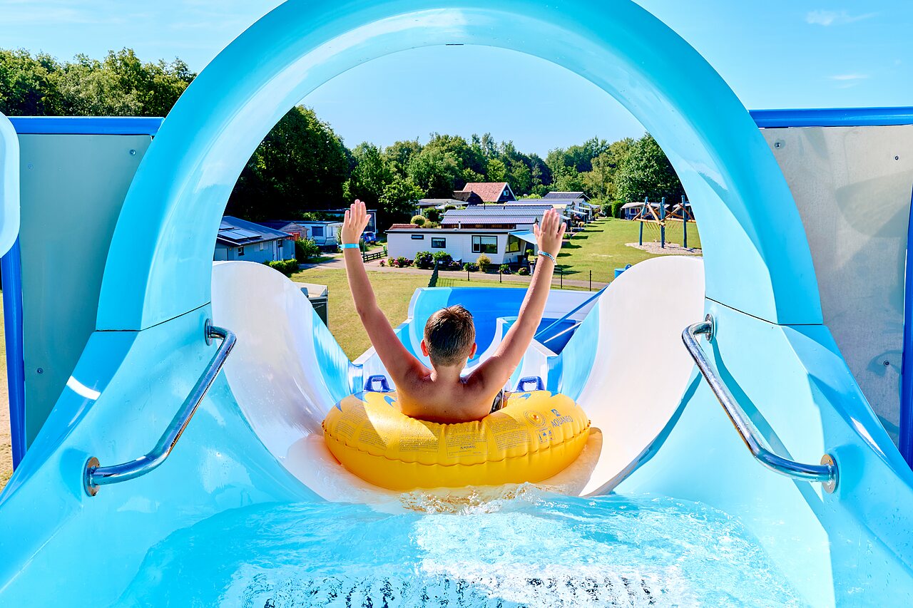 Water slide with child on tube at CAPFUN De Eikenhof campsite in Paasloo/Oldemarkt.