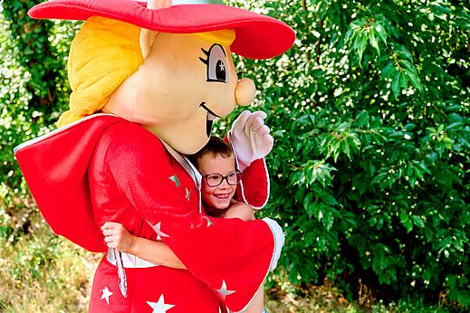 Smiling child hugging the mascot at CAPFUN De Eikenhof campsite in Paasloo/Oldemarkt.