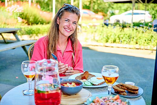 Smiling woman having lunch on the restaurant terrace at CAPFUN De Eikenhof campsite in Paasloo/Oldemarkt.
