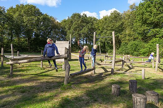 Children playing on a wooden adventure playground at CAPFUN De Eikenhof campsite in Paasloo/Oldemarkt.