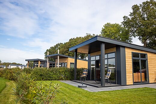 Modern mobile homes with terraces and chairs at CAPFUN De Eikenhof campsite in Paasloo/Oldemarkt.