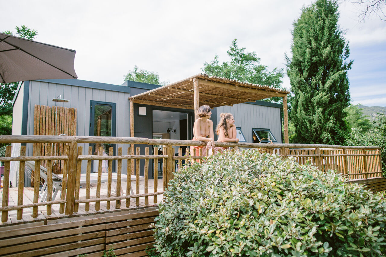 Modern mobile home, wooden deck, outdoor shower at LIBRANOO Naturiste Belezy campsite.