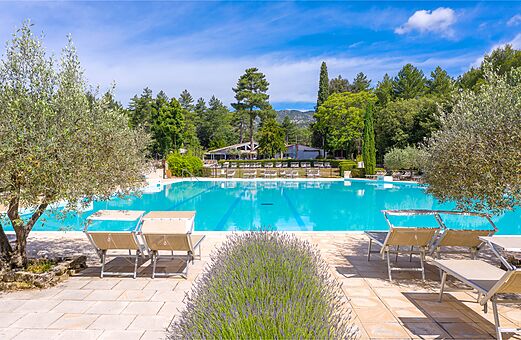 Large outdoor swimming pool with chairs at LIBRANOO Naturiste Belezy campsite in Bédoin (84).