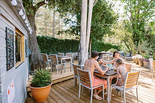 Naturist family having lunch on the terrace at the bar of LIBRANOO Naturiste Belezy campsite in Bédoin (84).