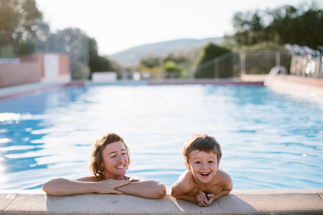 Smiling family in the swimming pool at LIBRANOO Naturiste Sabliere campsite in Barjac (30).