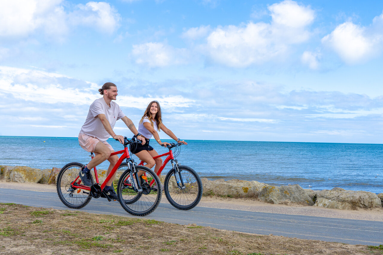 Couple cycling at CAPFUN Donjon de Lars campsite in Courseulles-sur-Mer (14).