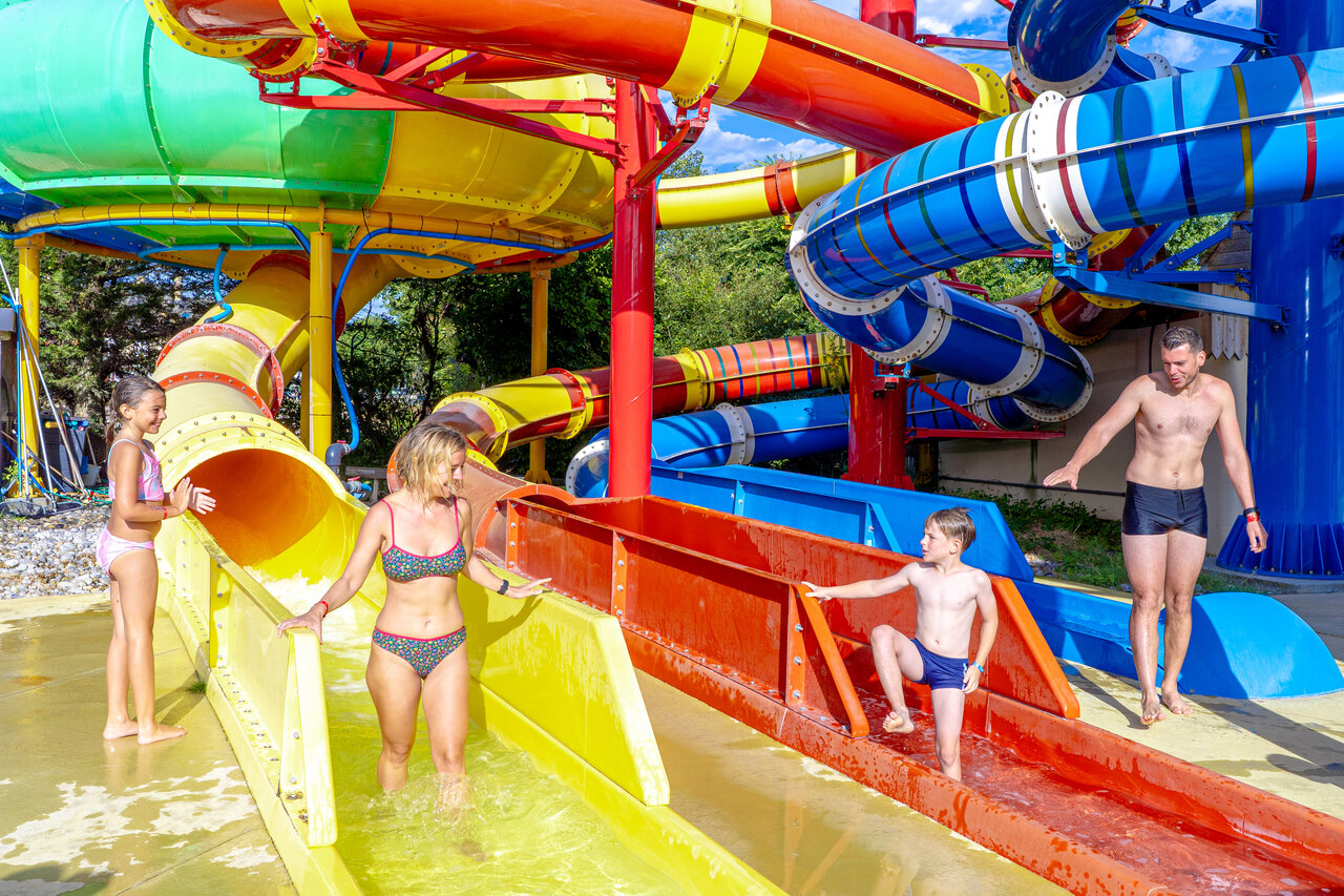 Colorful water slides and family enjoying the pool at CAPFUN Donjon de Lars campsite in Courseulles-sur-Mer (14).