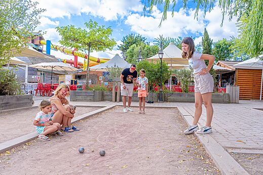 Family playing p�tanque on a dedicated court at camping CAPFUN Donjon de Lars in Courseulles-sur-Mer (14).