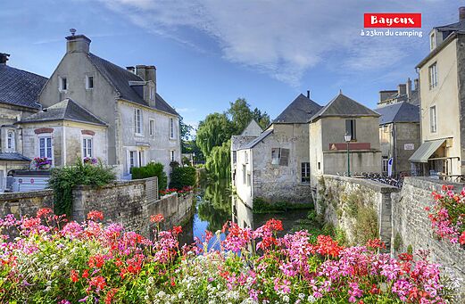 Flowery canal and historic houses in Bayeux, a city to visit in Normandy.