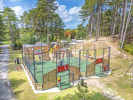 Multi-sport court with children playing basketball and football at CAPFUN Dune Fleurie campsite in Quend Plage (80).