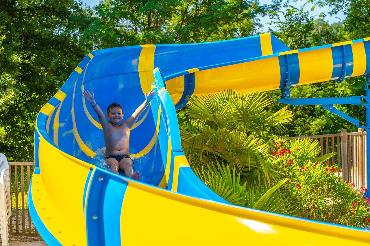 Happy child on blue and yellow water slide at CAPFUN Duravel in Duravel.