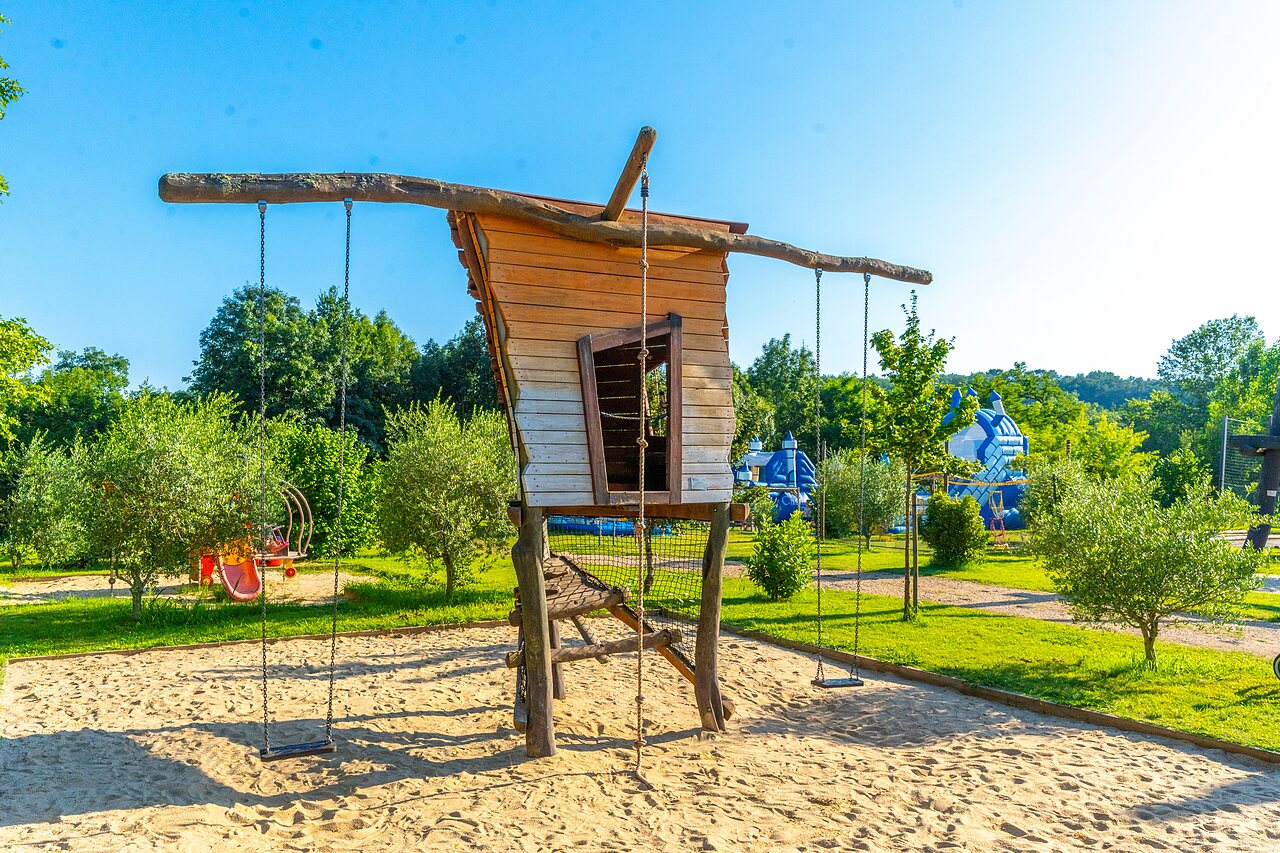 Playground with wooden hut, swings and bouncy castles at CAPFUN Duravel (46).