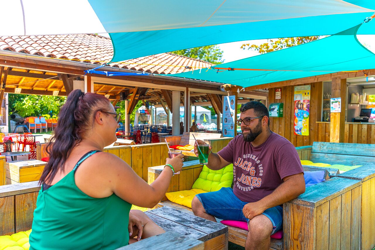 Couple toasting drinks at the bar of CAPFUN Duravel campsite in Duravel (46).