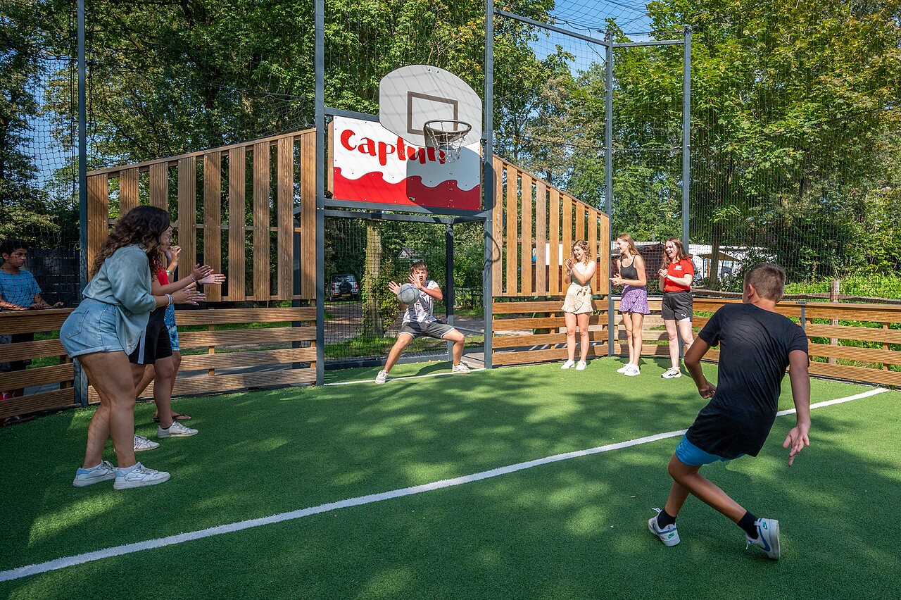 Young people playing basketball on Capfun multisport court at CAPFUN Eibernest campsite in Eibergen.