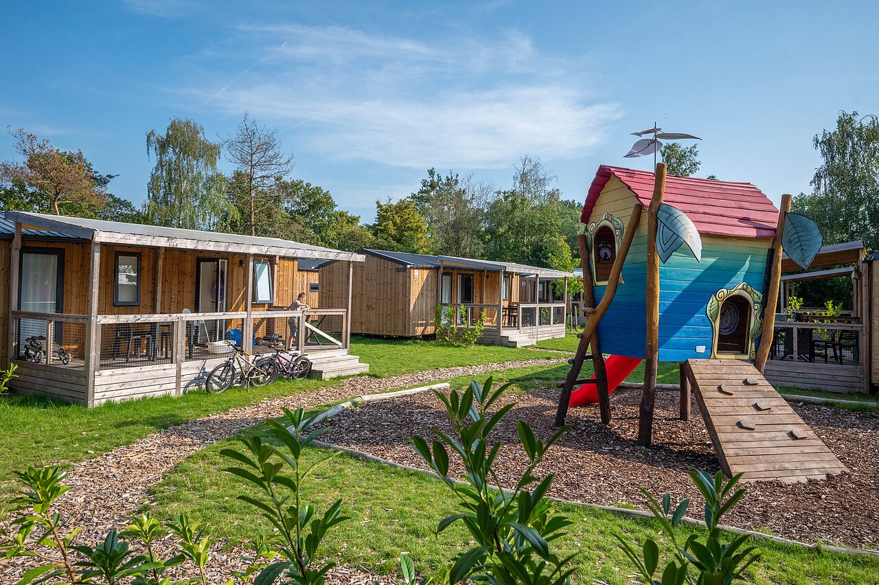 Wooden mobile homes with terrace and playground at CAPFUN Eibernest campsite in Eibergen.