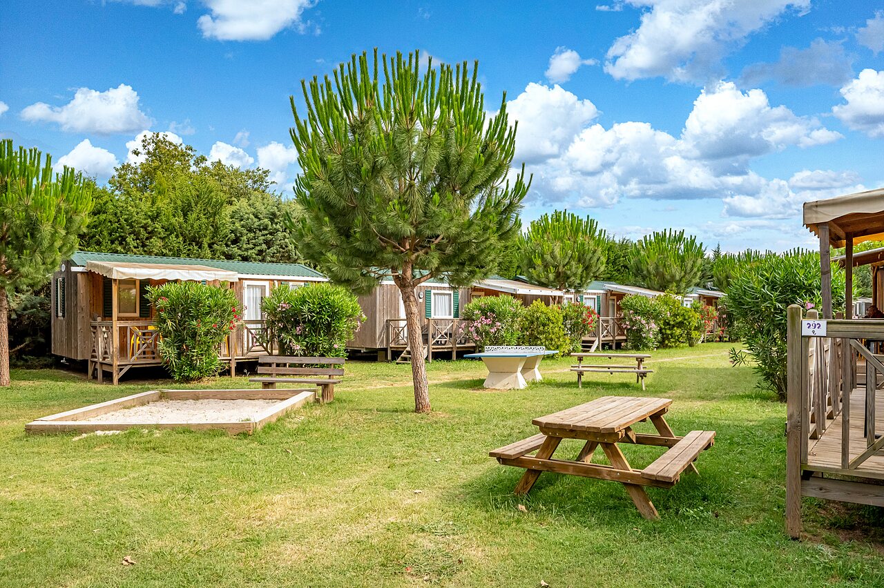 Wooden mobile homes, picnic table, play area at CAPFUN El Moli campsite.