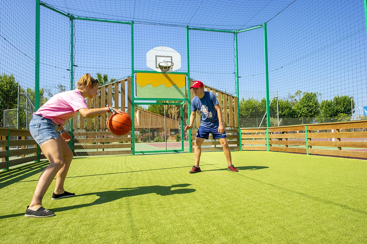 Young people playing basketball on multisport court at CAPFUN El Moli campsite in Elne (66).