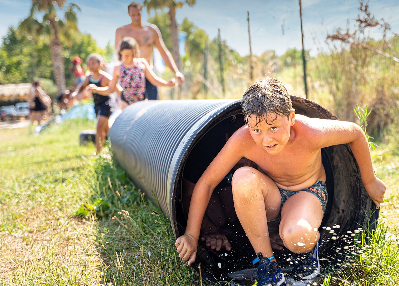 Child exiting a splashing water tunnel at CAPFUN El Moli campsite in Elne (66).