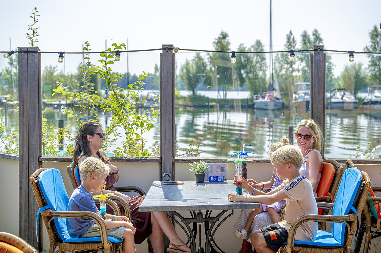 Family at the bar, refreshing drinks, lake view at CAPFUN Erkemederstrand campsite in Zeewolde.