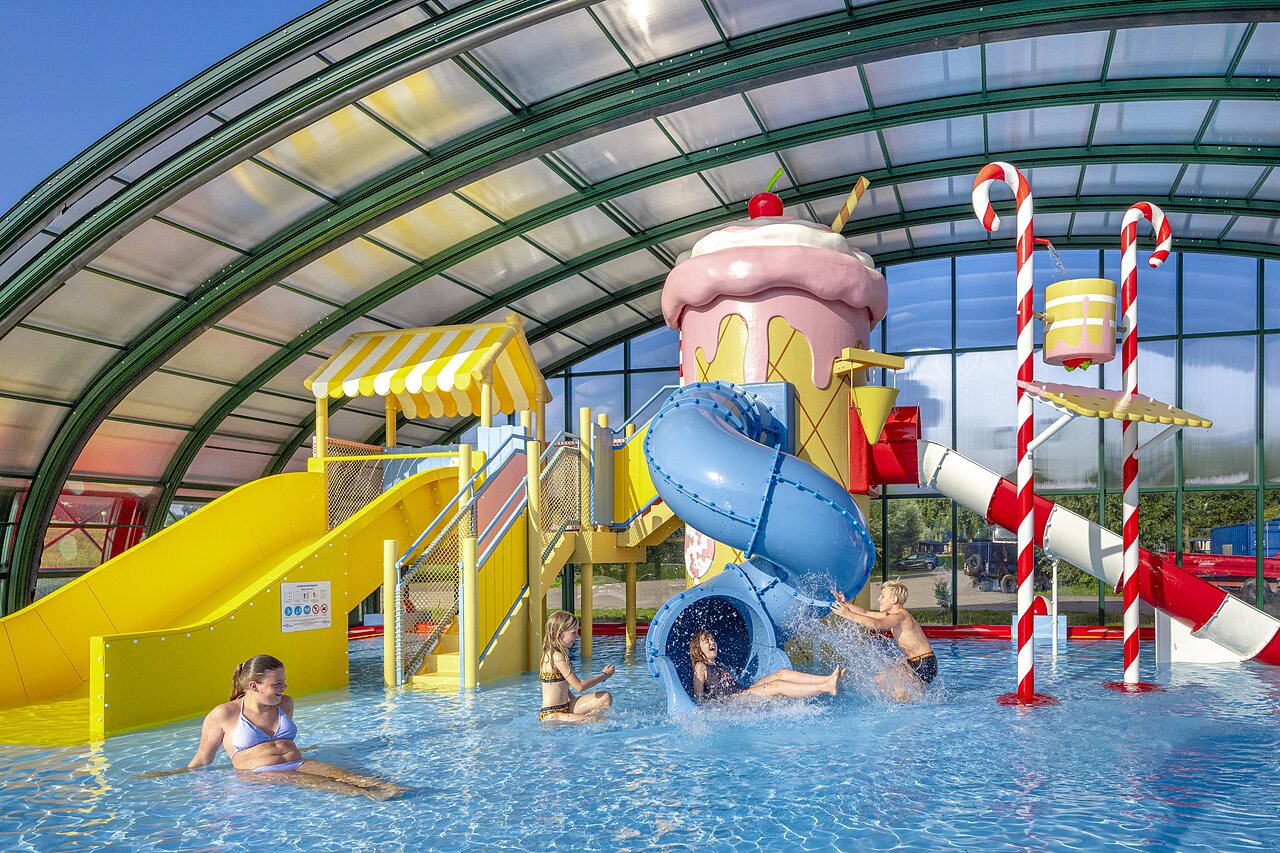 Covered pool with slides and water games at CAPFUN Erkemederstrand campsite in Zeewolde.