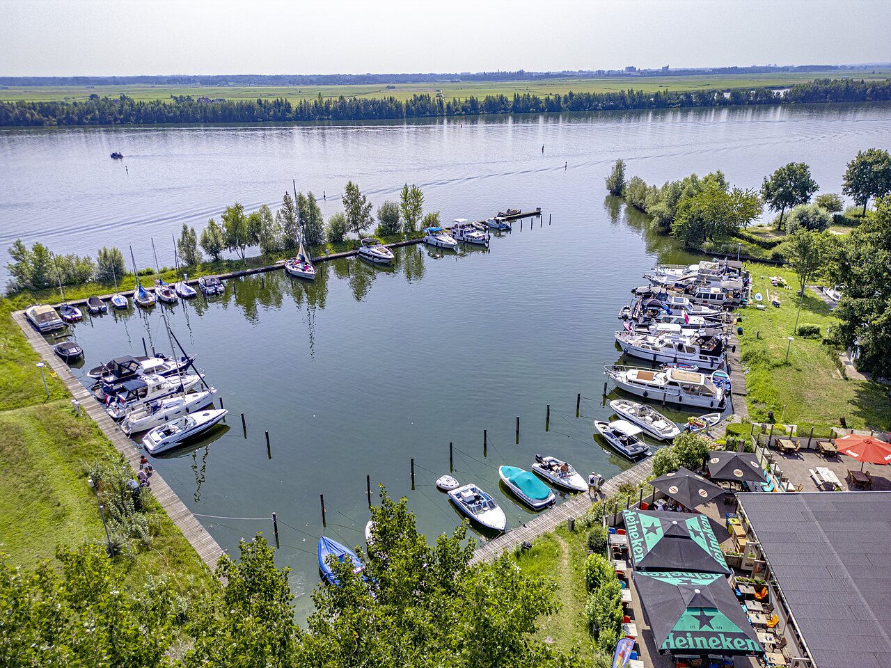 Marina with docked boats and lakeside bar at CAPFUN Erkemederstrand campsite in Zeewolde.
