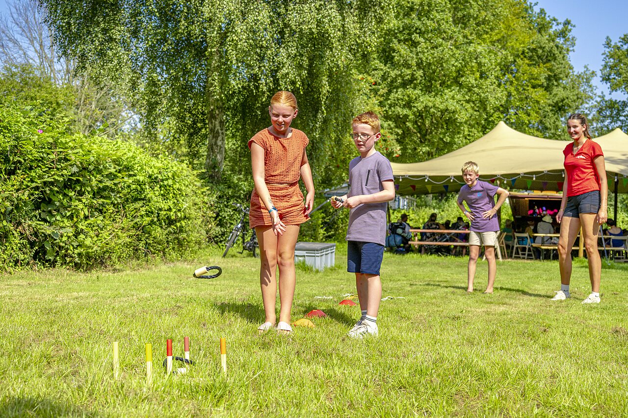 Children playing ring toss game on the grass at CAPFUN Erkemederstrand campsite in Zeewolde.