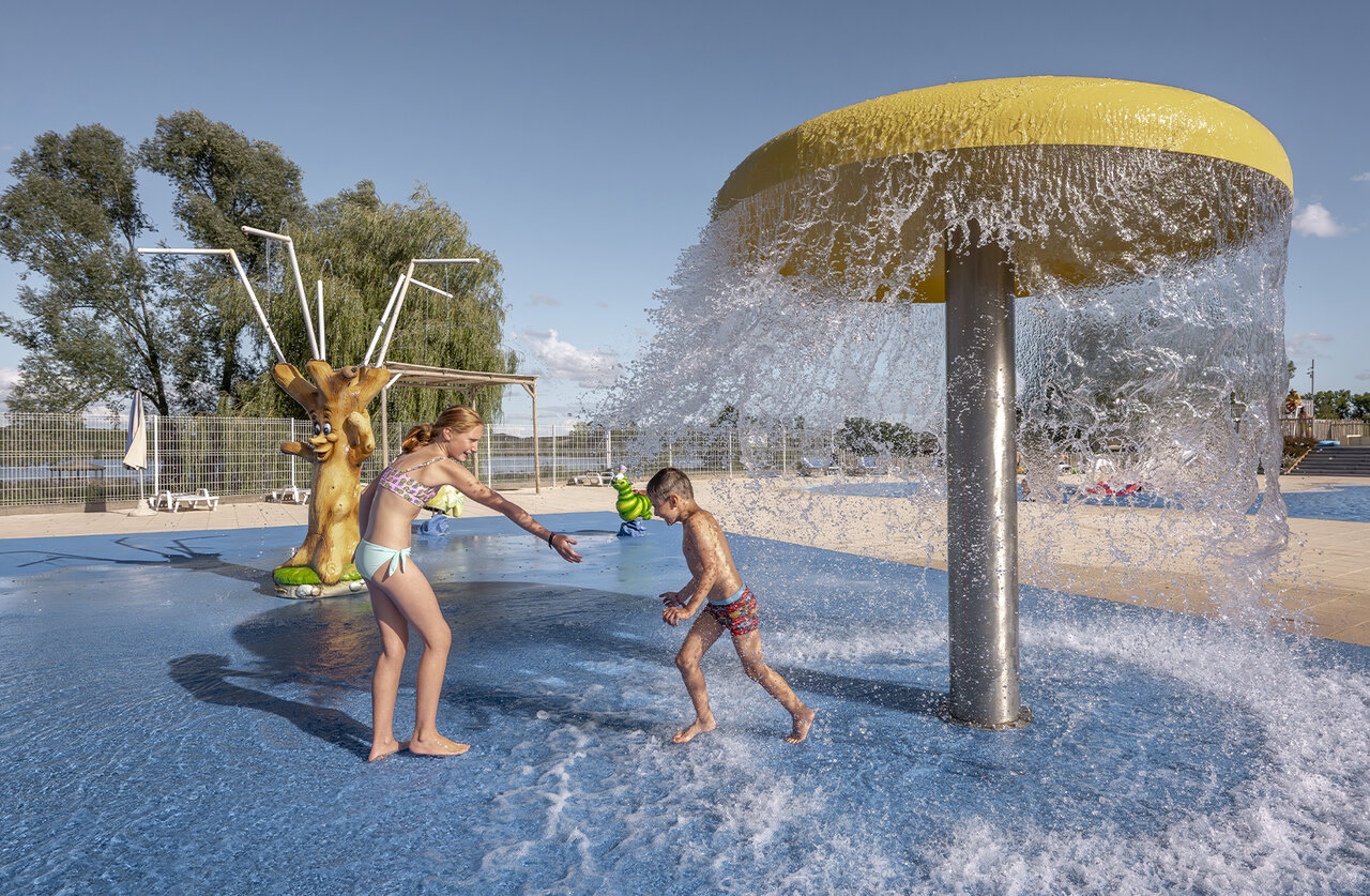 Water play area with children at CLICOCHIC Etang de la Mutche campsite.