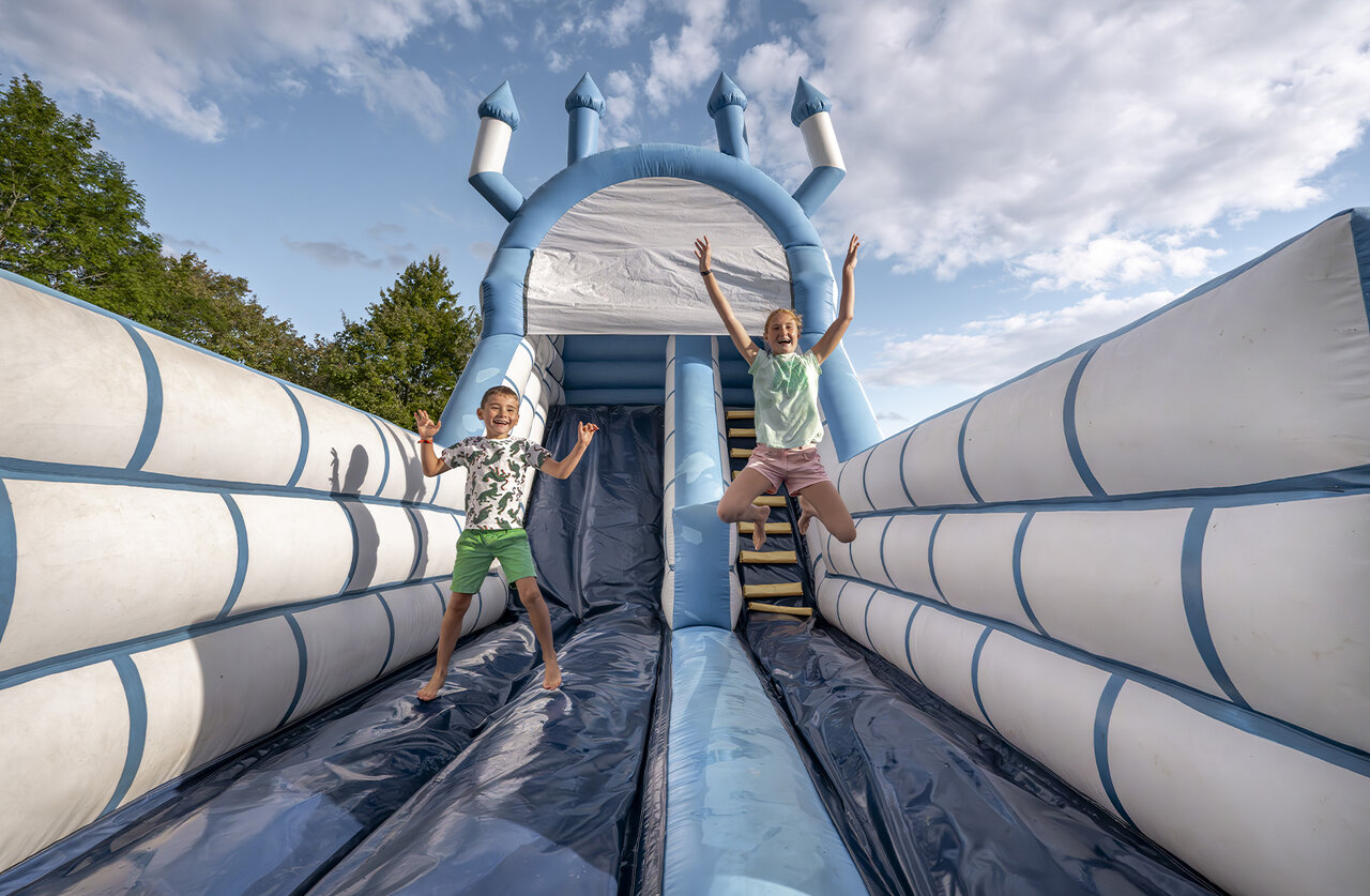 Happy children jumping on inflatable castle at campsite CLICOCHIC Etang de la Mutche in HARPRICH (57).