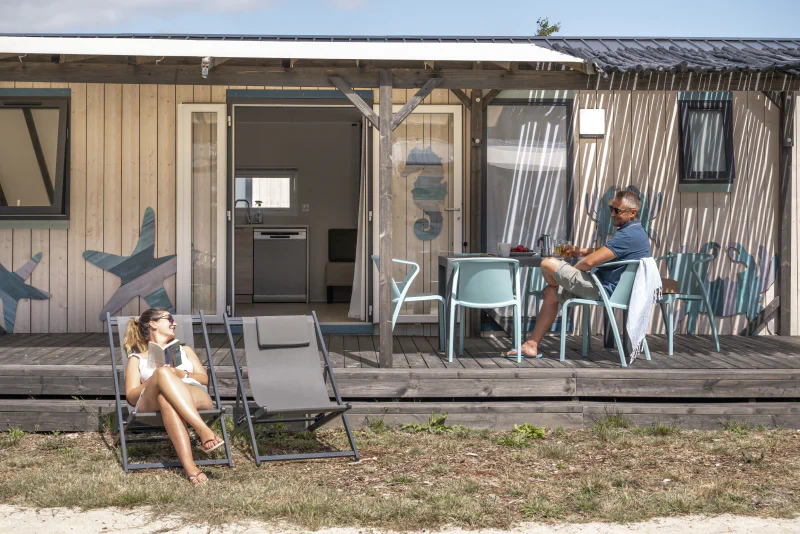 Couple relaxing on mobile home terrace, CLICOCHIC Etoile de Mer, Asserac (44).